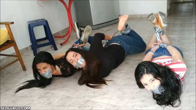 An angry woman is bound and gagged while she receives a lesbian foot worship by two girls