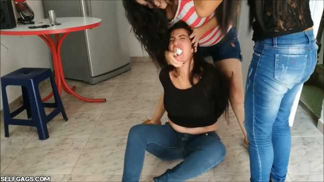 An angry woman is bound and gagged while she receives a lesbian foot worship by two girls