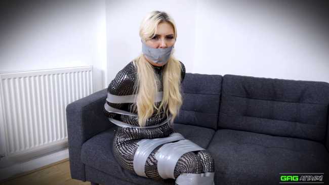Blonde woman in a catsuit stuck in tape bondage
