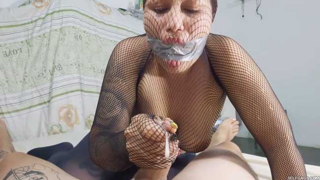 Gagged girl gives handjob while encased in fishnet pantyhose