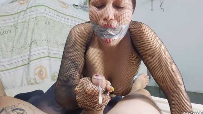 Gagged girl gives handjob while encased in fishnet pantyhose