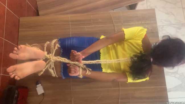 Barefoot girl gagged and hog-tied on table