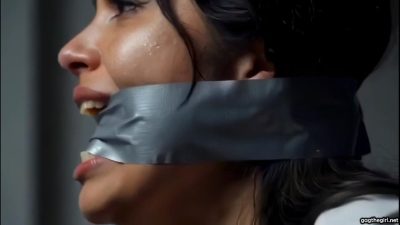 Profile close-up of dark-haired beauty with shiny duct tape cleave gag stretched tight across her mouth