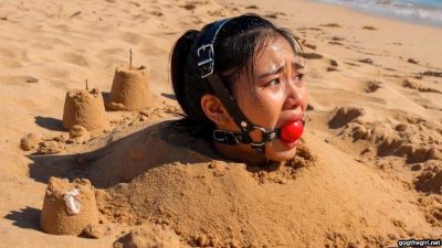 cared ballgagged woman desperately looking around while buried in the sand on a remote beach