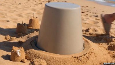 Southeast Asian woman completely hooded with bucket over her head, buried alone in the sand with harness ball gag