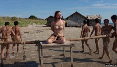 Group of tribal warriors carrying bound and ballgagged university student on wooden pole across the beach