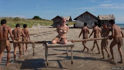 Helpless ballgagged woman roped to carrying pole being paraded by native warriors in front of island huts